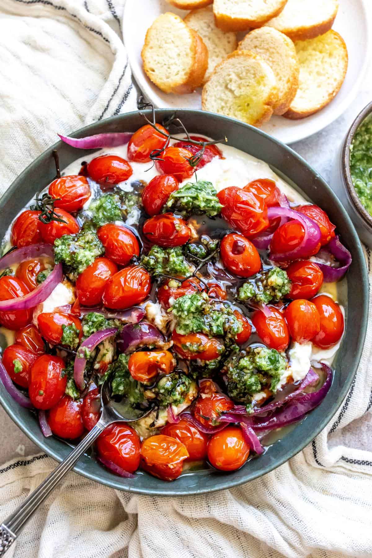 Pesto Burrata in a green bowl with bread to the side.