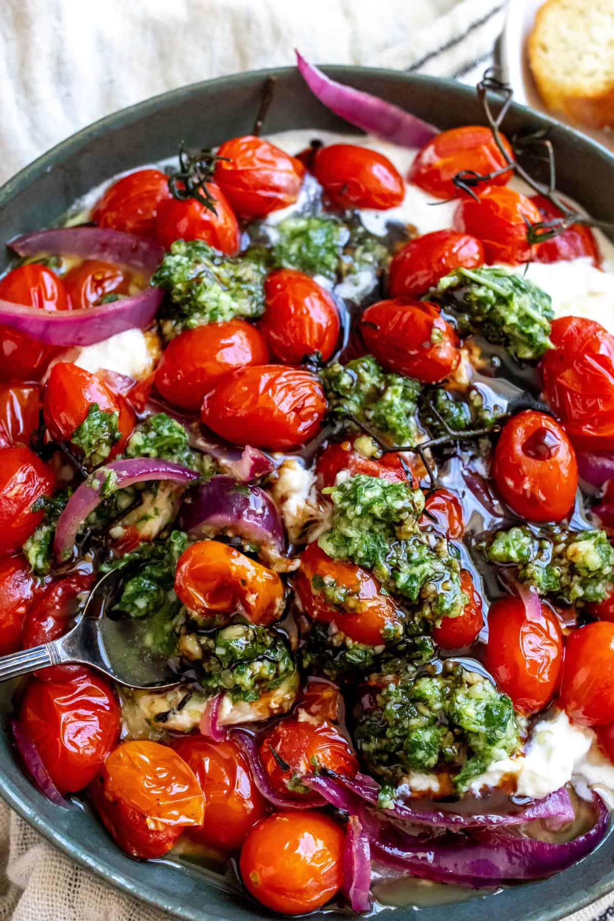 Pesto Burrata in a green bowl with bread to the side, up close photo. 