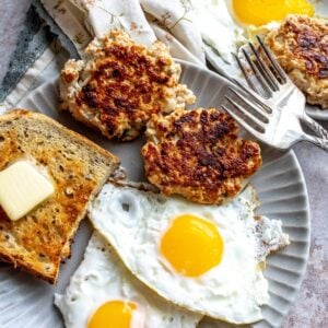 An image of chicken apple sausage with eggs and bread on a plate.