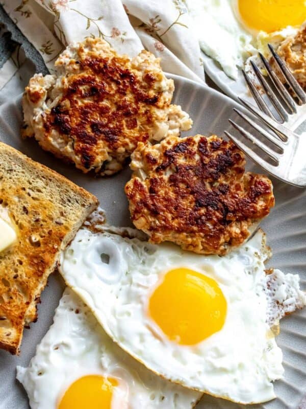 An image of chicken apple sausage with eggs and bread on a plate.