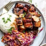 Grilled pork belly served with rice and coleslaw.