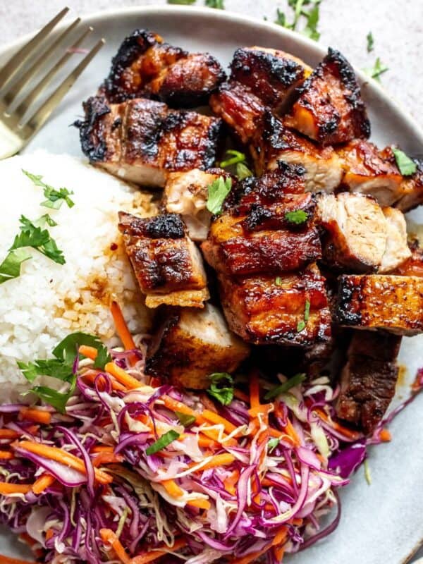 Grilled pork belly served with rice and coleslaw.