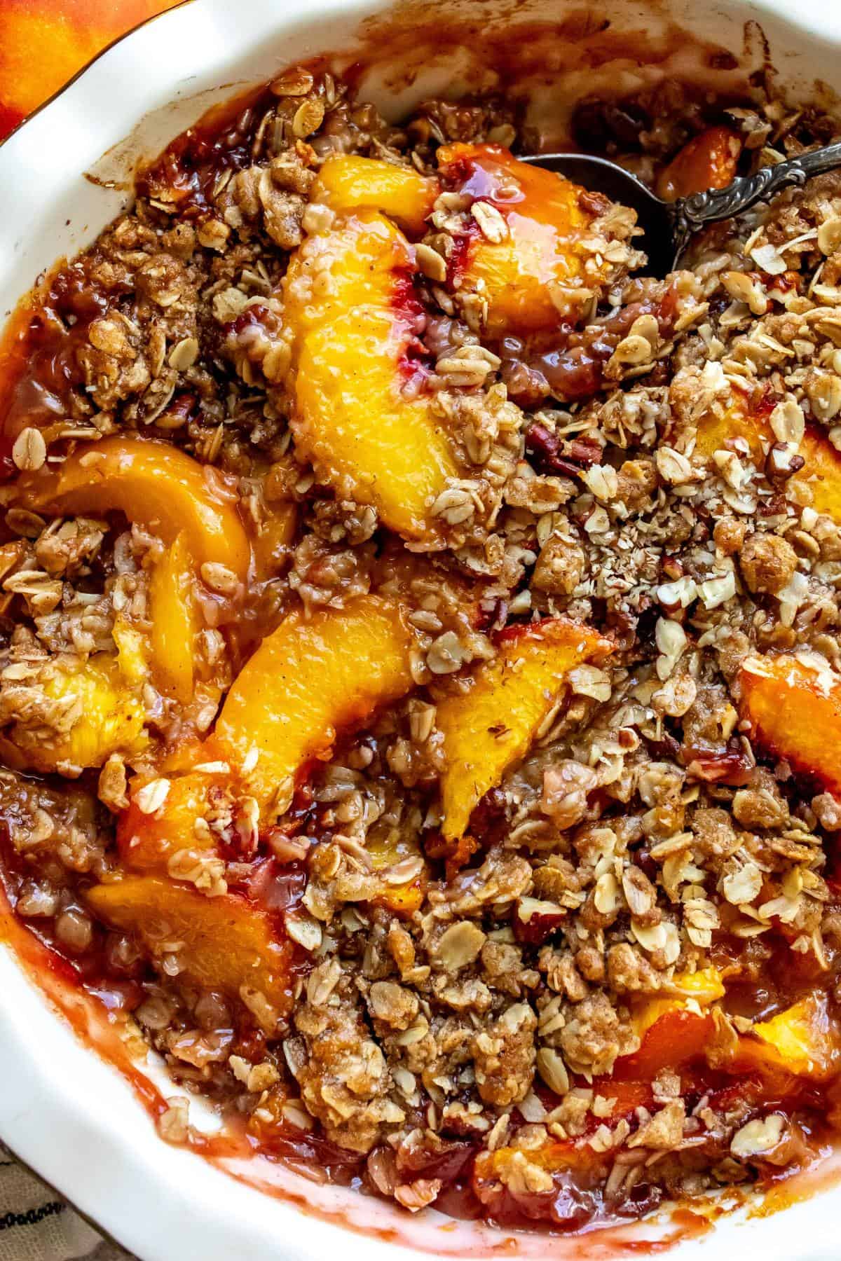 Up close photo of peach crisp with the browned oatmeal crumble on top. 