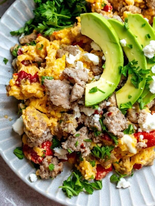 An image of turkey sausage on a plate with eggs, avocados, and veggies.