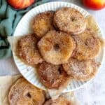 An overhead image of a stack of apple donuts on a plate.