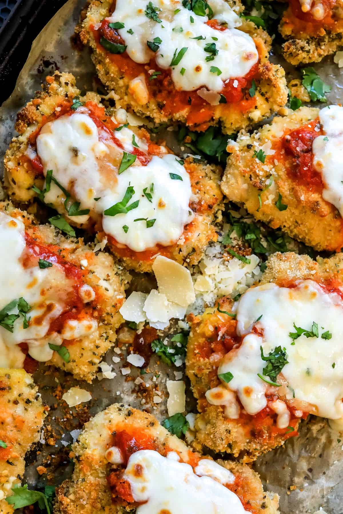 Parmesan Chicken Thighs on a baking sheet with parchment paper up close with parsley on top. 