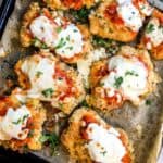 Parmesan Chicken Thighs on a baking sheet with parchment paper.