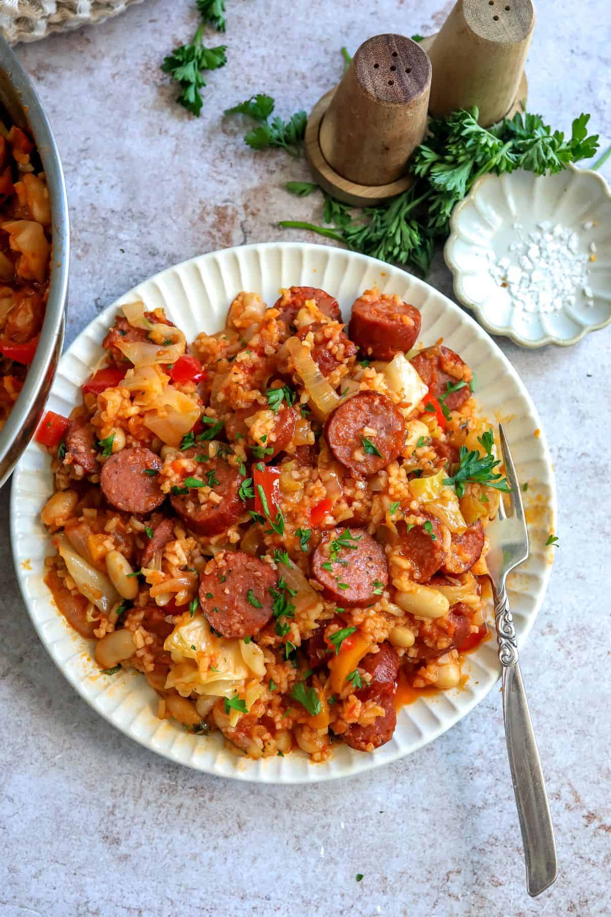 White plate with slow cooker sausage casserole on it and a fork to the side. 