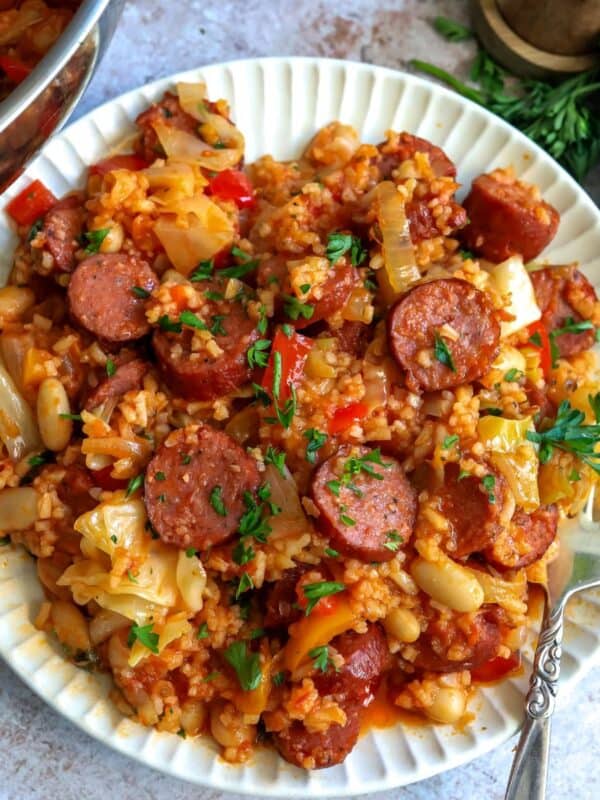 White plate with slow cooker sausage casserole on it and a fork to the side.