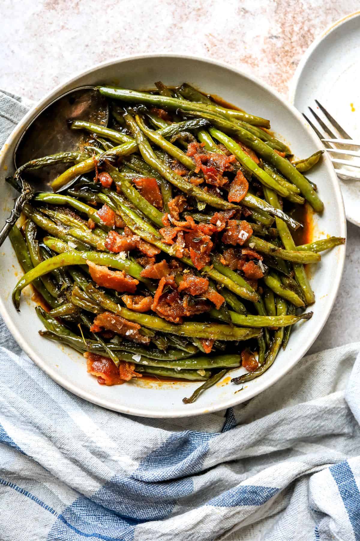 An overhead image of crack green beans on a plate, with bacon bits on top.