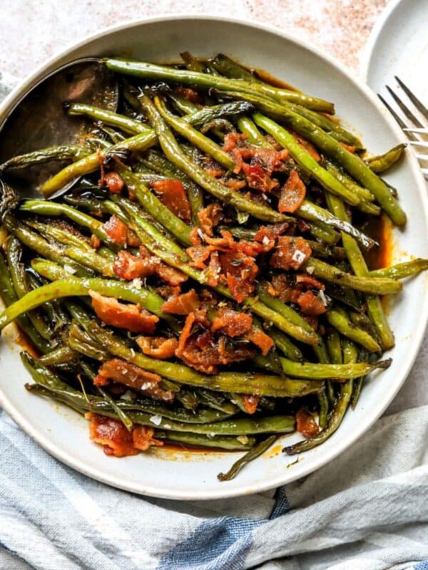 An overhead image of crack green beans on a plate, with bacon bits on top.