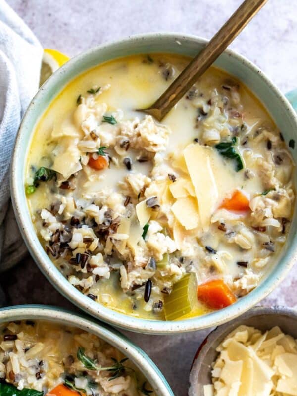 Soup bowls filled with Creamy Chicken Wild Rice Soup and a towel on the side, up close