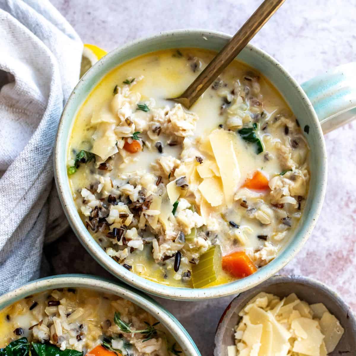 Soup bowls filled with Creamy Chicken Wild Rice Soup and a towel on the side, up close