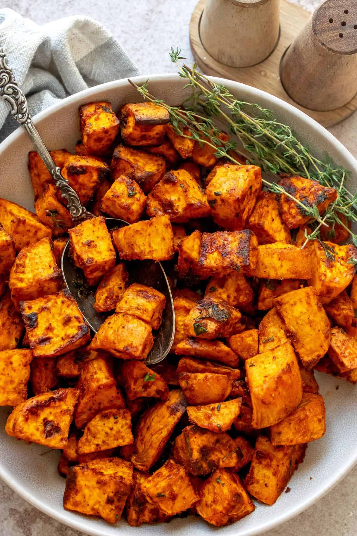 Crispy Roasted Sweet Potatoes in a bowl with a silver antique spoon. 