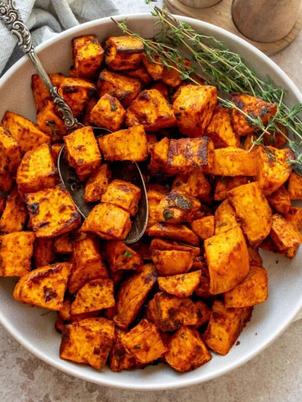 Crispy Roasted Sweet Potatoes in a bowl with a silver antique spoon.