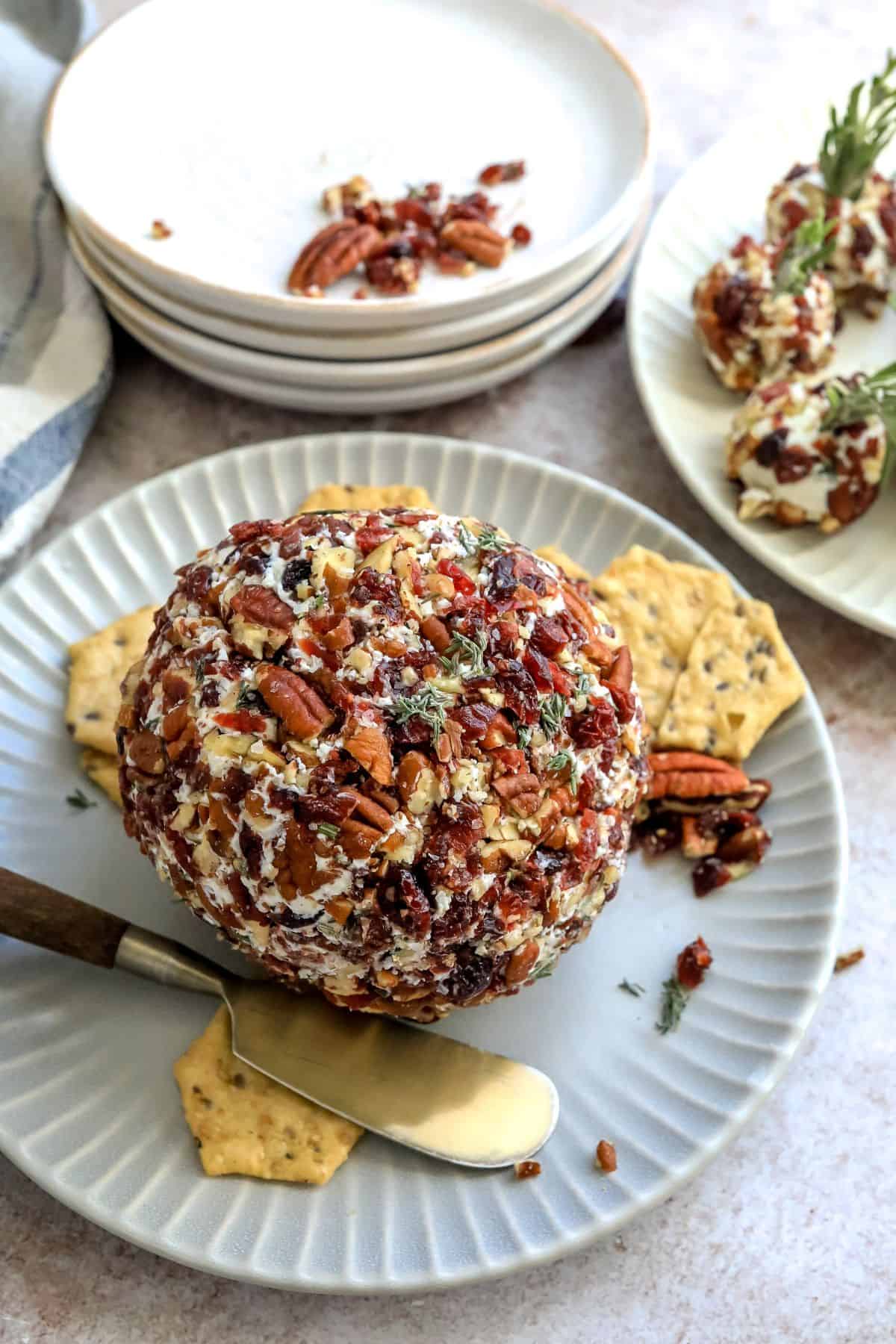 Grey plate with goat cheese ball on it and cranberries and pecans. 