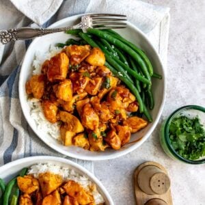 white bowl with Honey Bourbon Chicken and green beans.