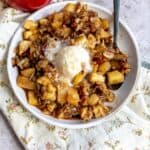 White plate with Slow Cooker Apple Crisp on it and melted ice cream.