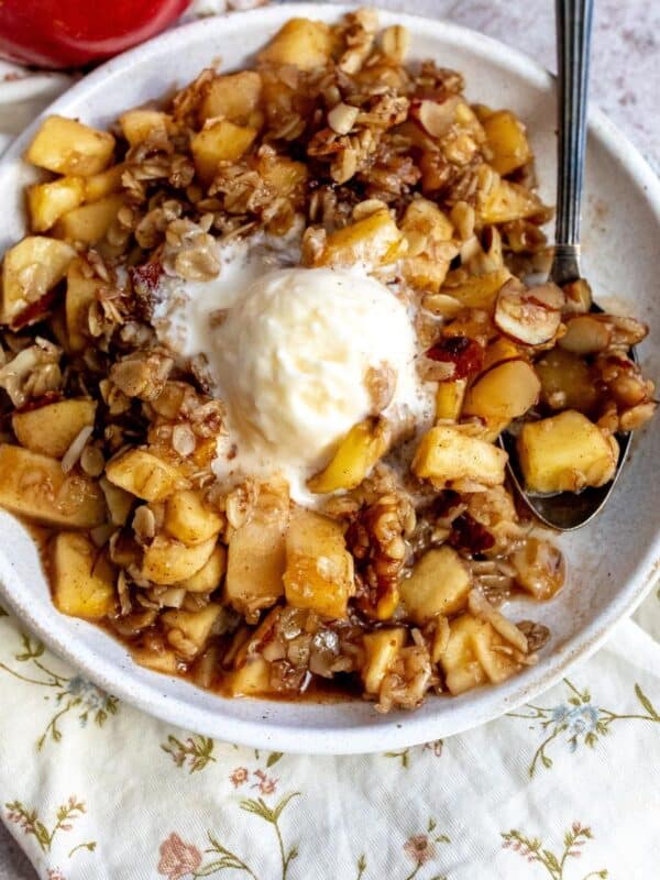 White plate with Slow Cooker Apple Crisp on it and melted ice cream.