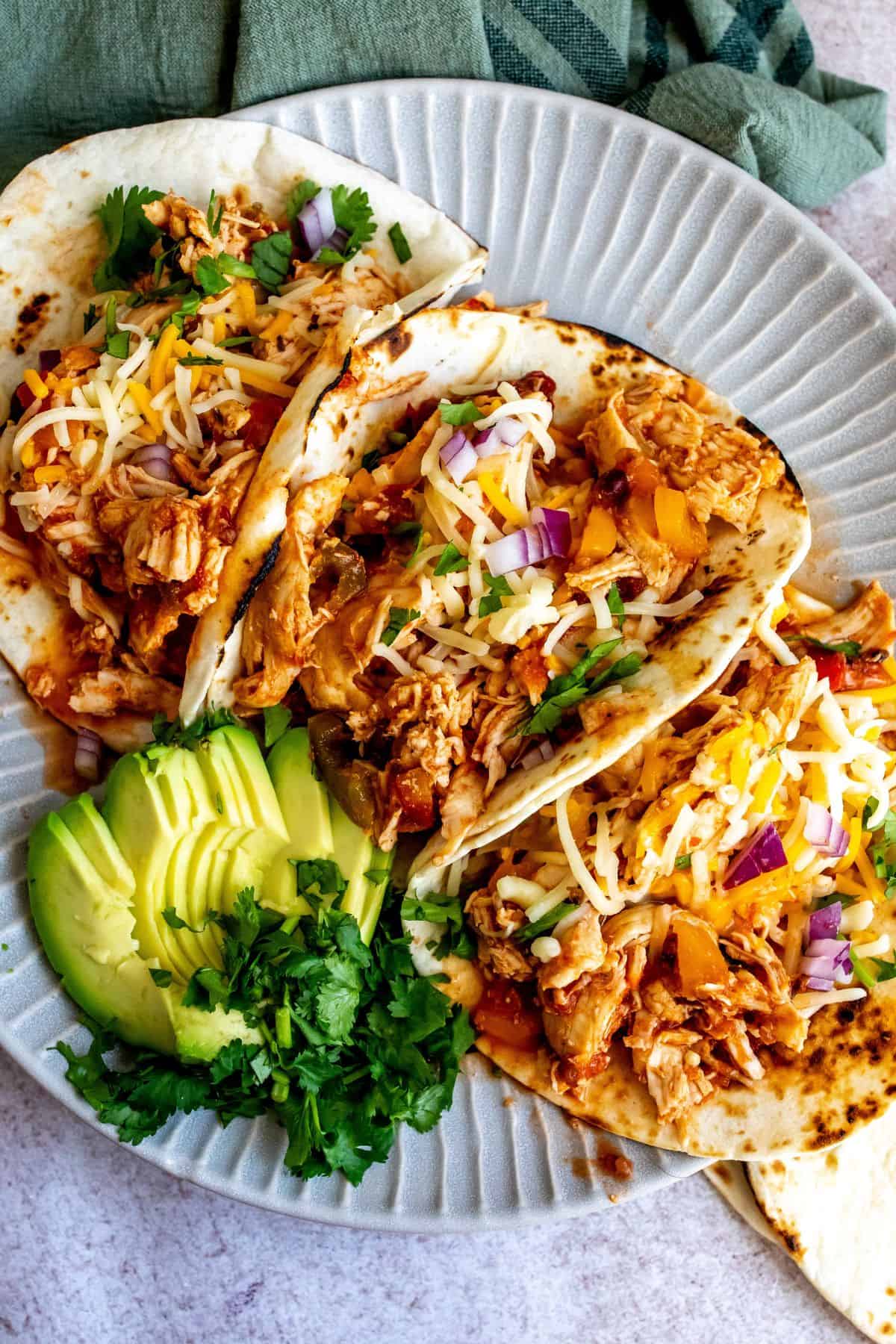 Plate with lines on it and three slow cooker chicken tacos. 