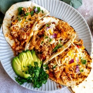 Plate with lines on it and three slow cooker chicken tacos.