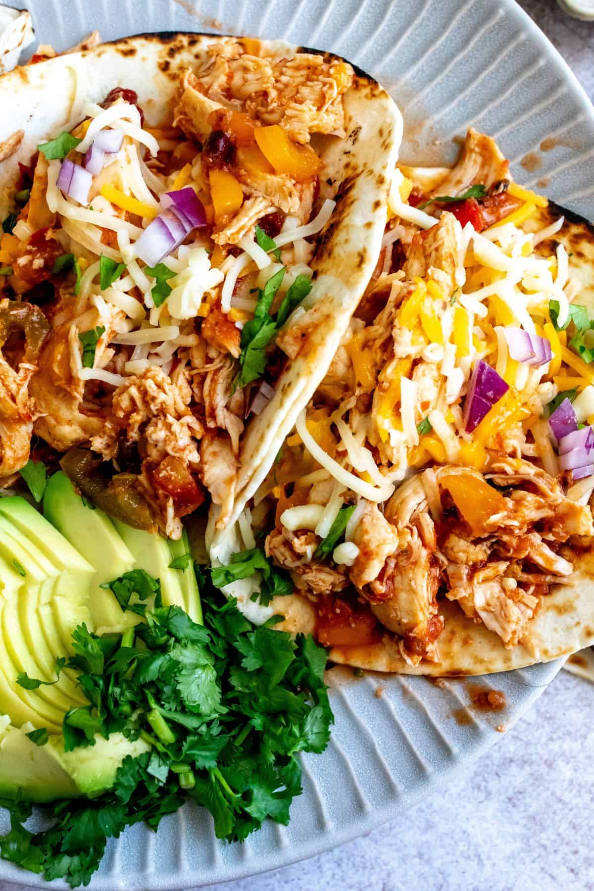 Plate with lines on it and three slow cooker chicken tacos up close photo. 