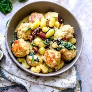 Grey bowl with Slow Cooker Tuscan Chicken Meatballs with Gnocchi in it. Parmesan on top.