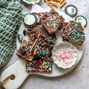 Christmas Bark on a white plate with sprinkles and Oreo cookies.