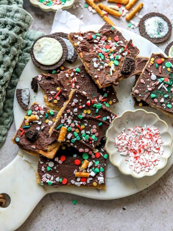 Christmas Bark on a white plate with sprinkles and Oreo cookies.