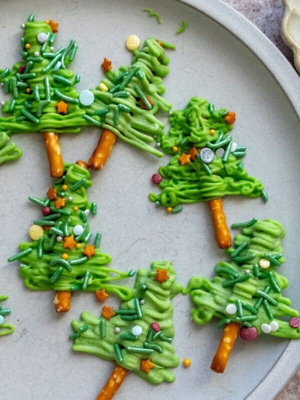 White plate with Pretzel Christmas Trees on it and sprinkles on the side.