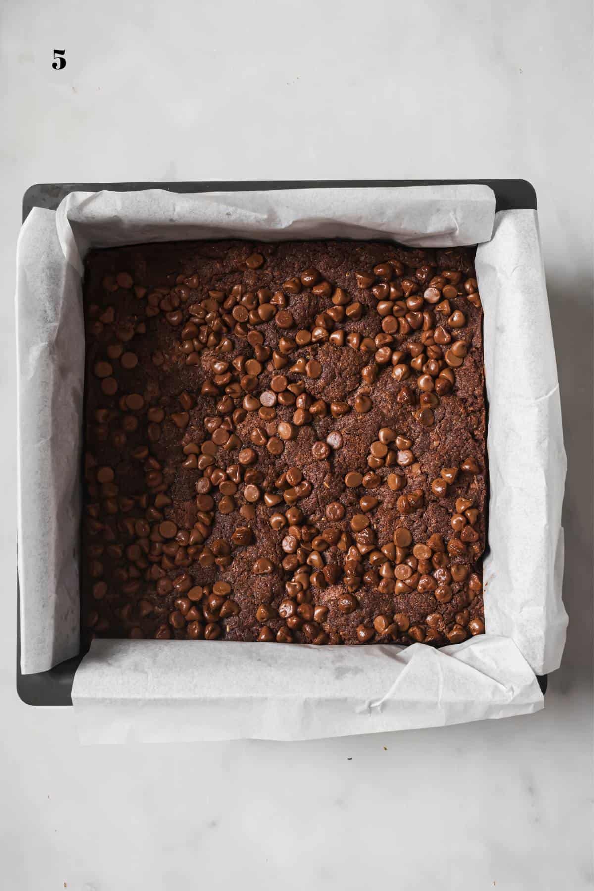 Chocolate Chocolate Chip Cookie Bars in a baking pan with white parchment paper.