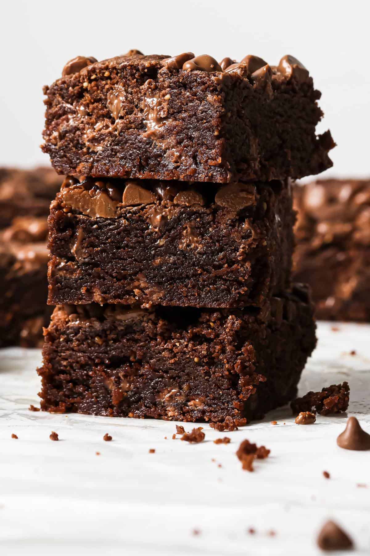 Chocolate Chocolate Chip Cookie Bars on a white counter, stacked up on each other.