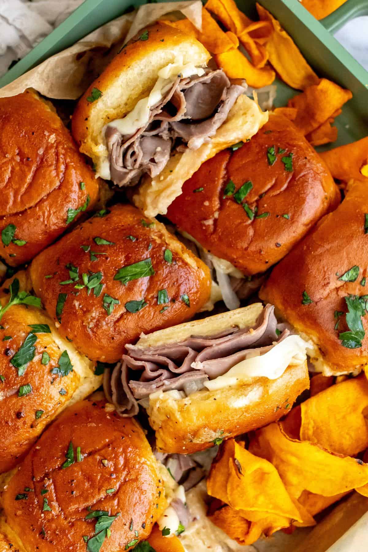 Up close photo of roast beef sliders on parchment paper. 