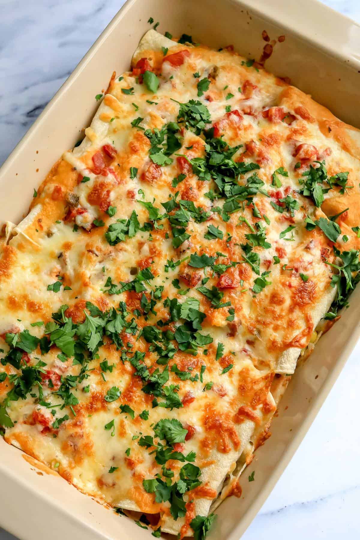 Cheesy White Enchiladas in a baking dish with bubbly cheese and cilantro. 