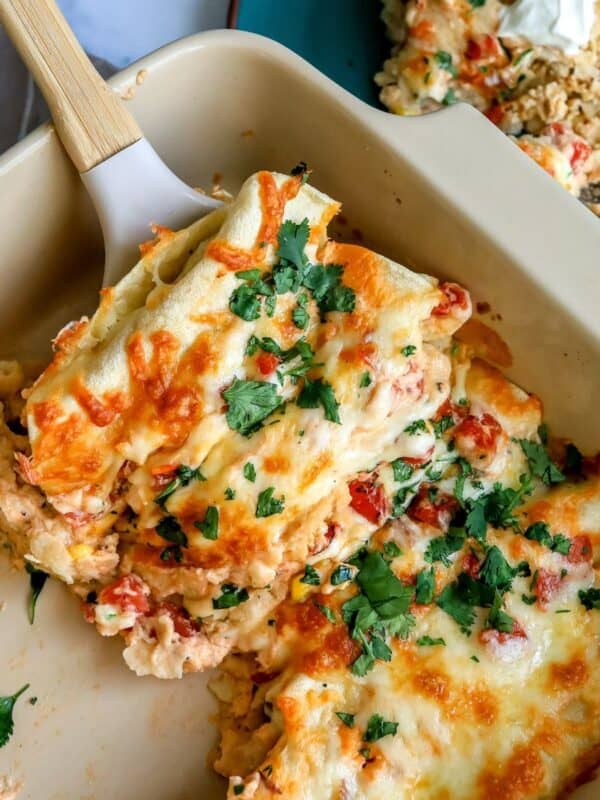 White Chicken Enchiladas up close in a baking dish with a spatula.