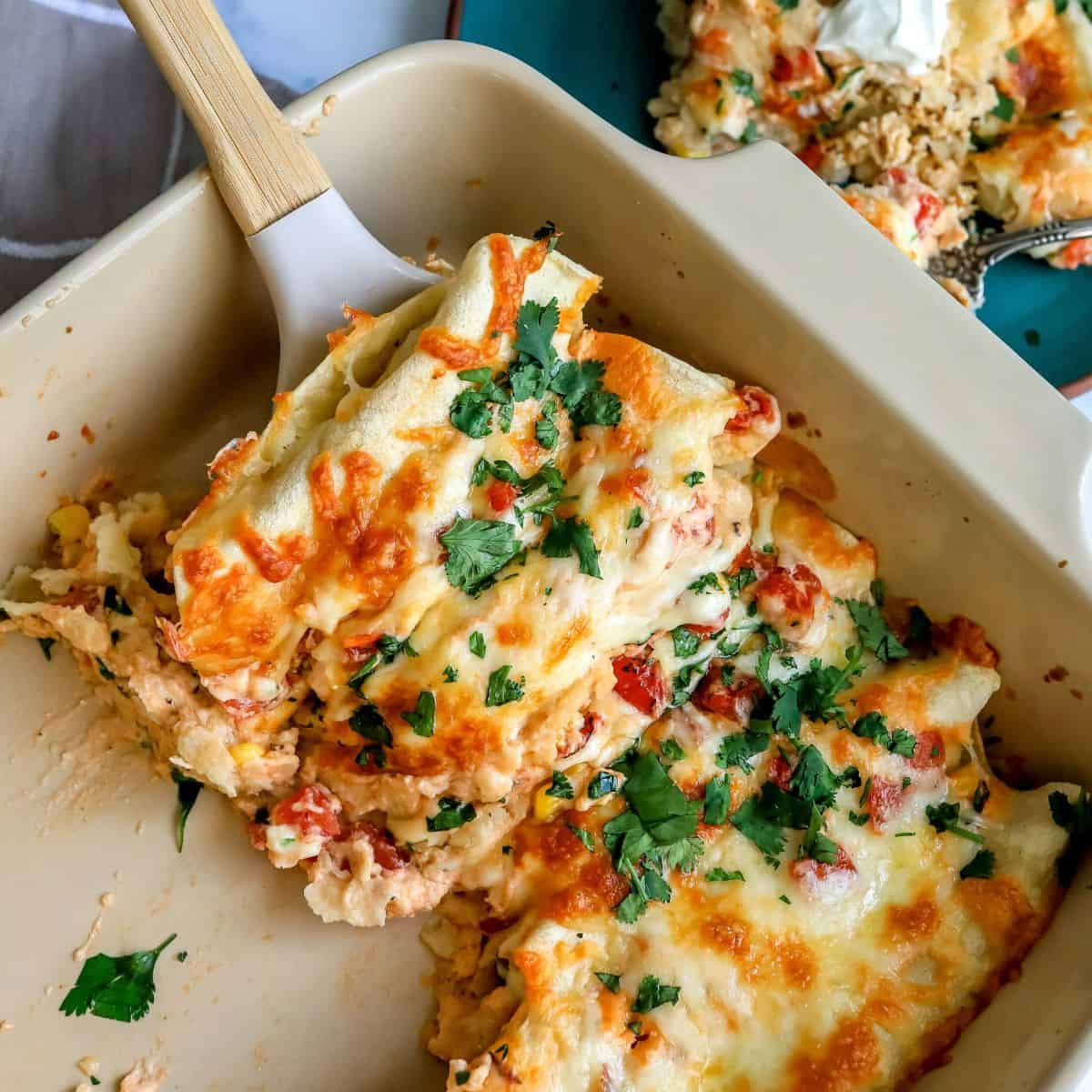 White Chicken Enchiladas up close in a baking dish with a spatula.