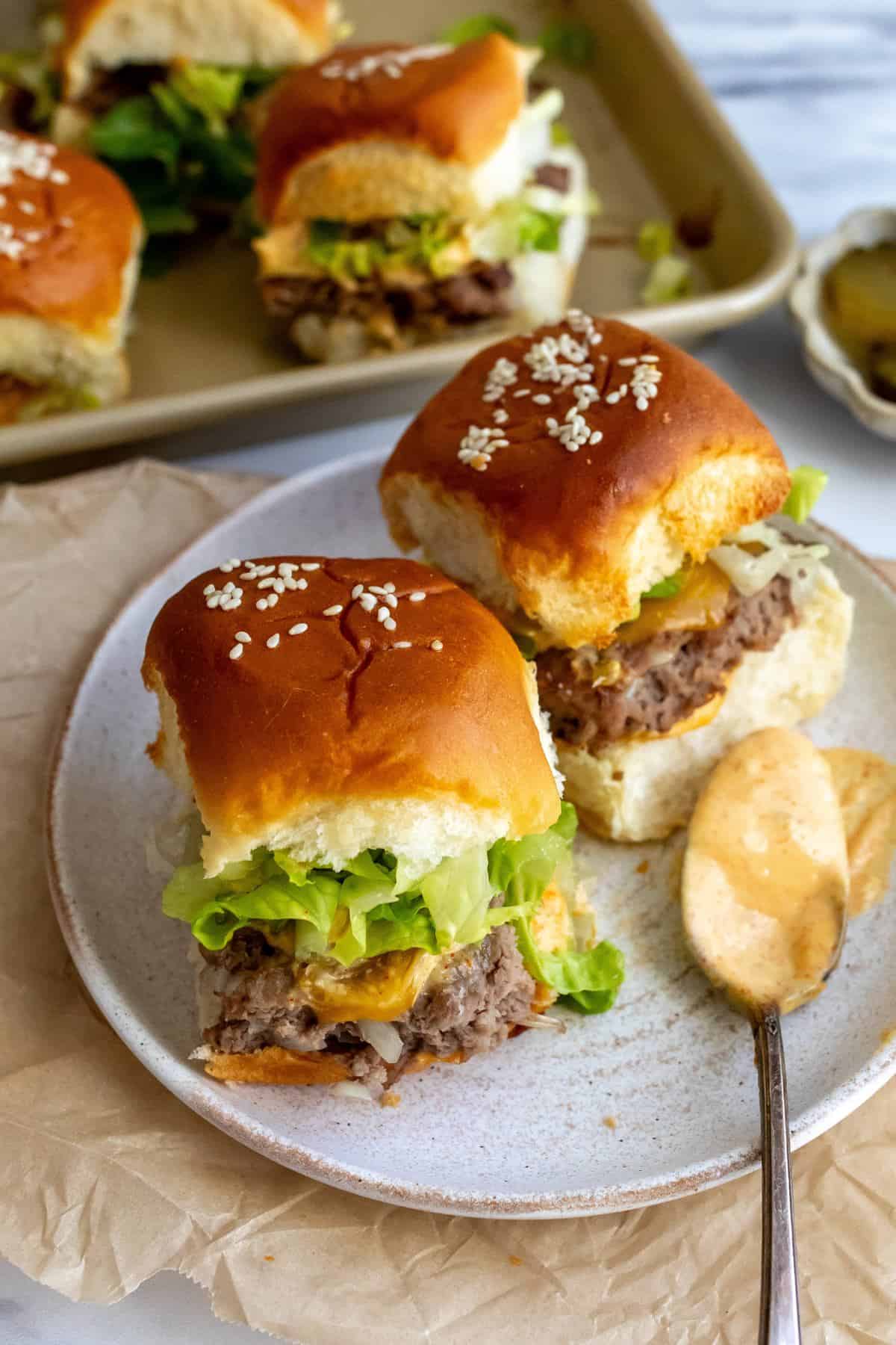 Big Mac Slider on a white ceramic plate with a saucy spoon on the side. 