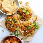 Chicken Tinga Toastadas on a white counter on parchment paper with jalapeños.