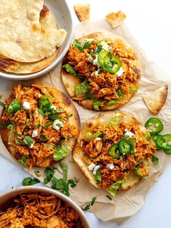 Chicken Tinga Toastadas on a white counter on parchment paper with jalapeños.