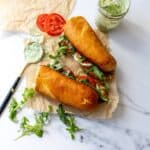 Green Goddess Caprese Melts on parchment paper with dressing to the side.