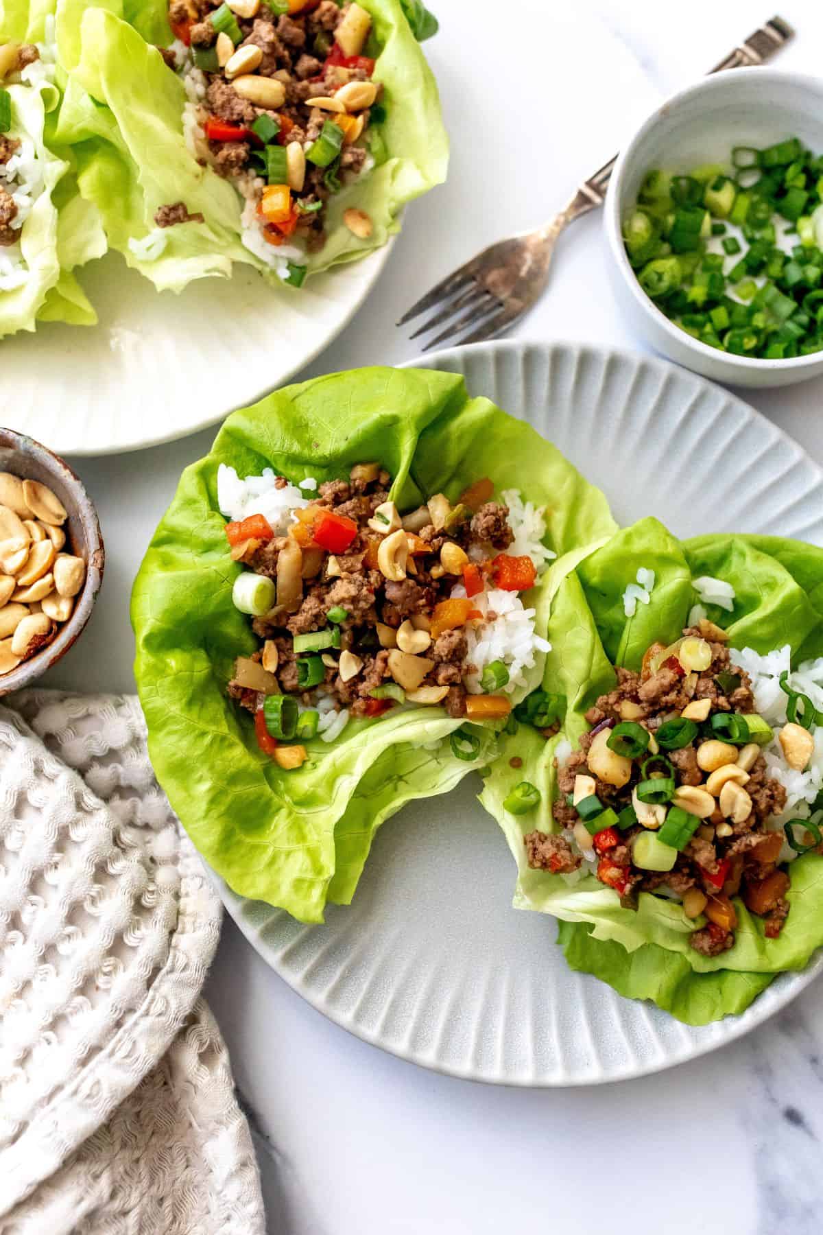 Ground Beef Lettuce Wraps on grey plates with a fork and onions on the side. 