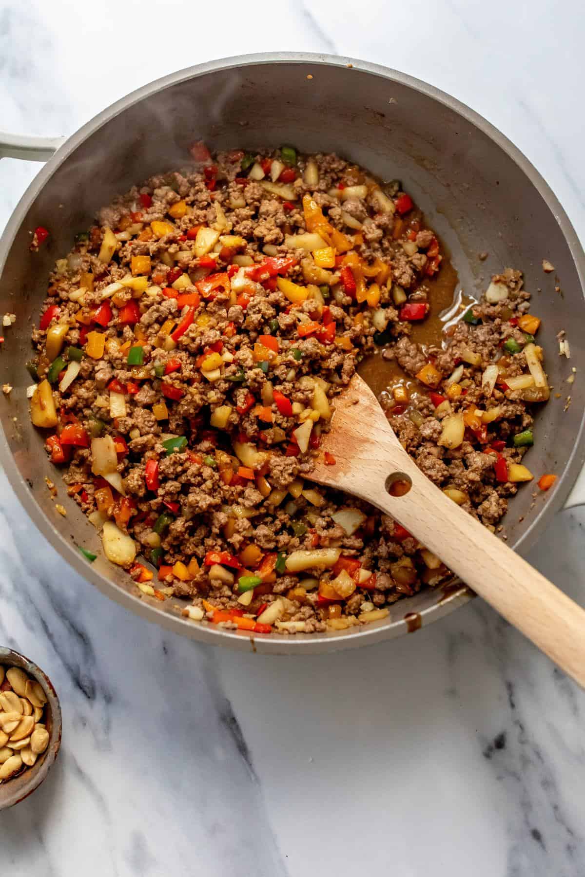 Ground beef mixture in a skillet with a wooden spatula. 