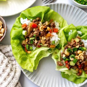 Ground Beef Lettuce Wraps on grey plates with a fork and onions on the side.