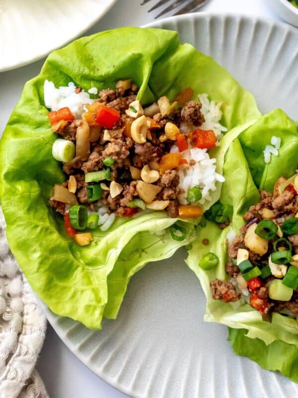 Ground Beef Lettuce Wraps on grey plates with a fork and onions on the side.