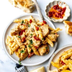 White ceramic plate with marry me chicken pasta on it and silver fork to the side.