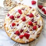 Raspberry Almond Cake on a white counter with raspberries and icing and forks to the side.