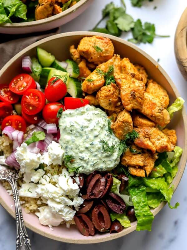 Pink ceramic bowls with Chicken Gyro in them and lots of colorful toppings.