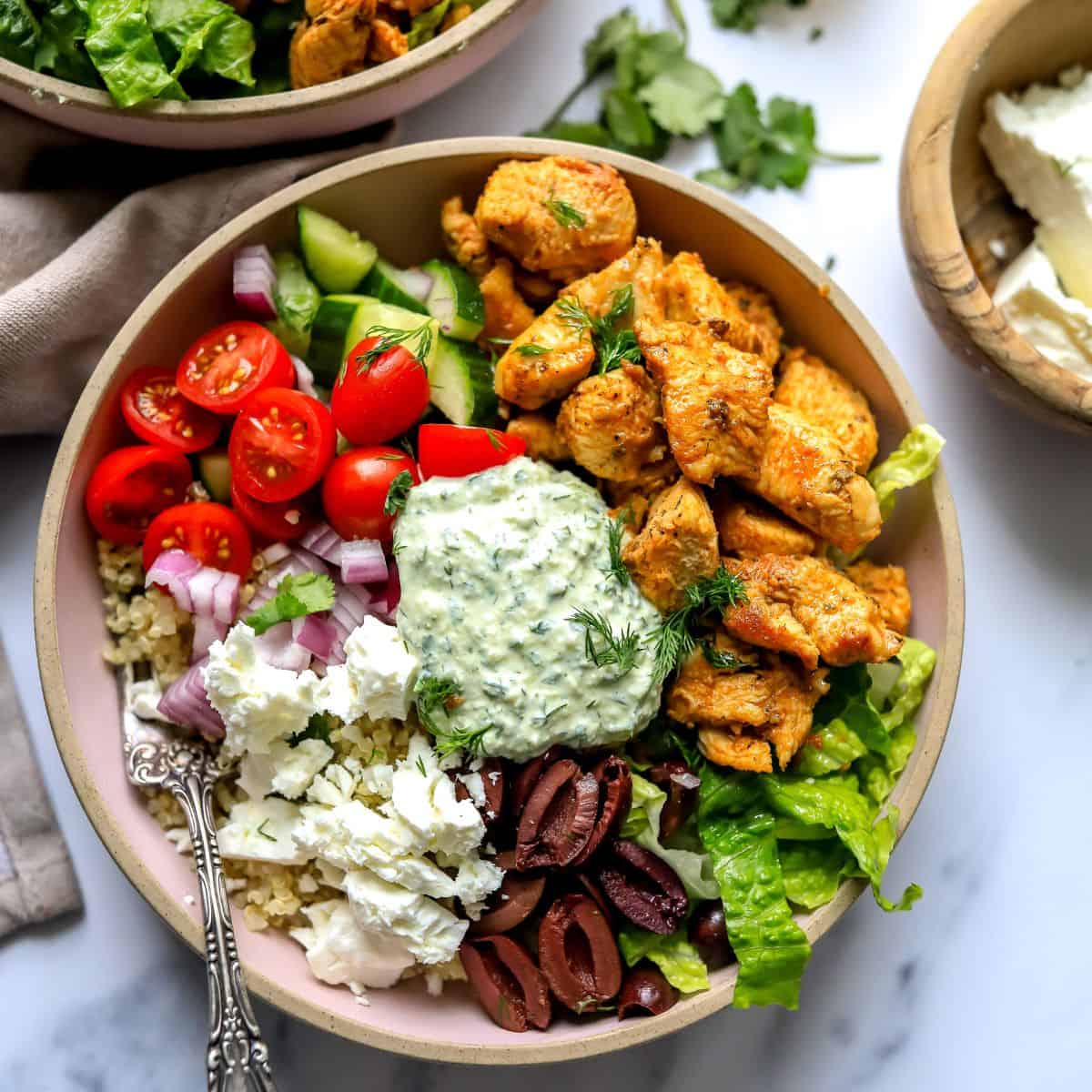 Pink ceramic bowls with Chicken Gyro in them and lots of colorful toppings.