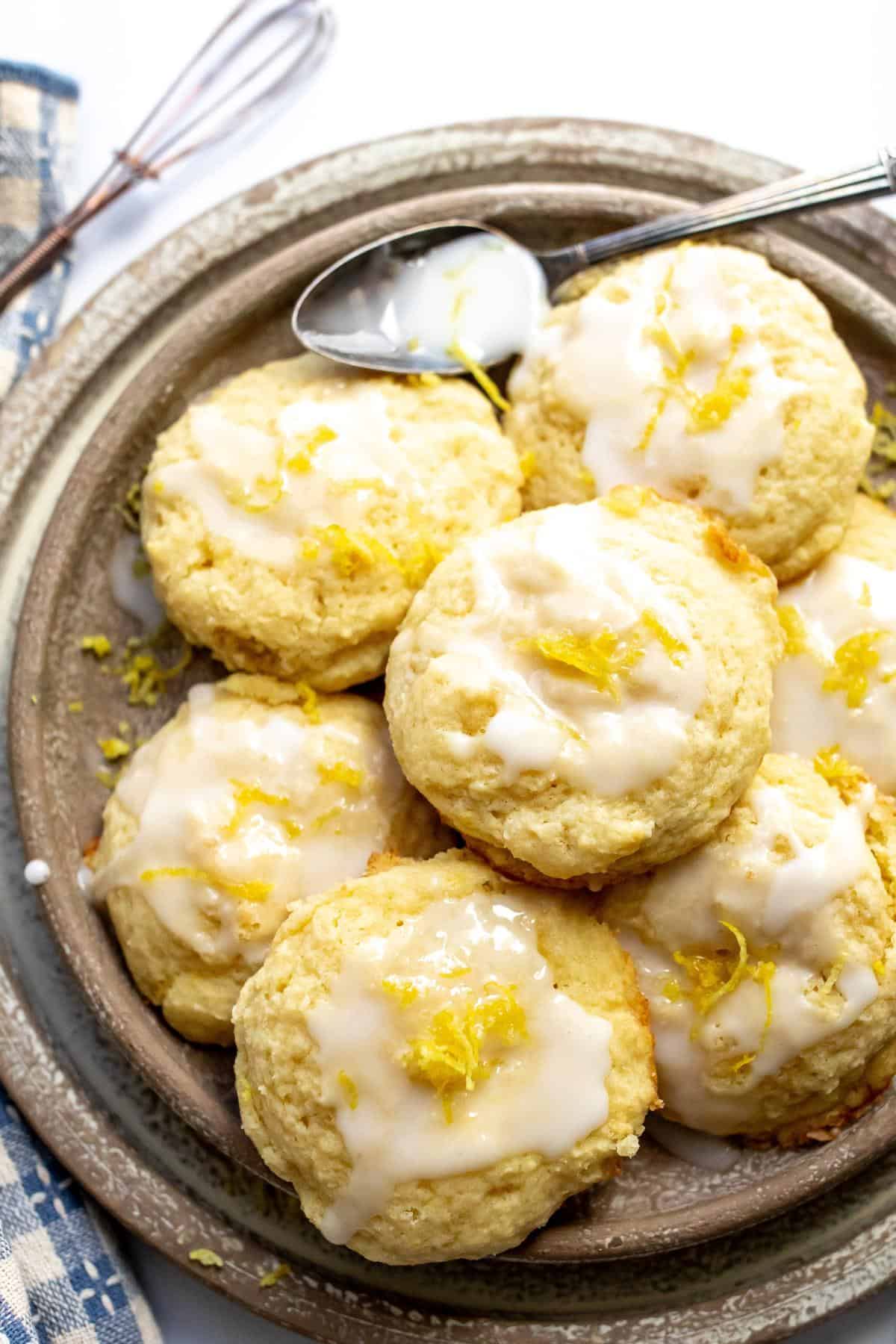 Lemon ricotta cookies on a beige plate with icing on top. 