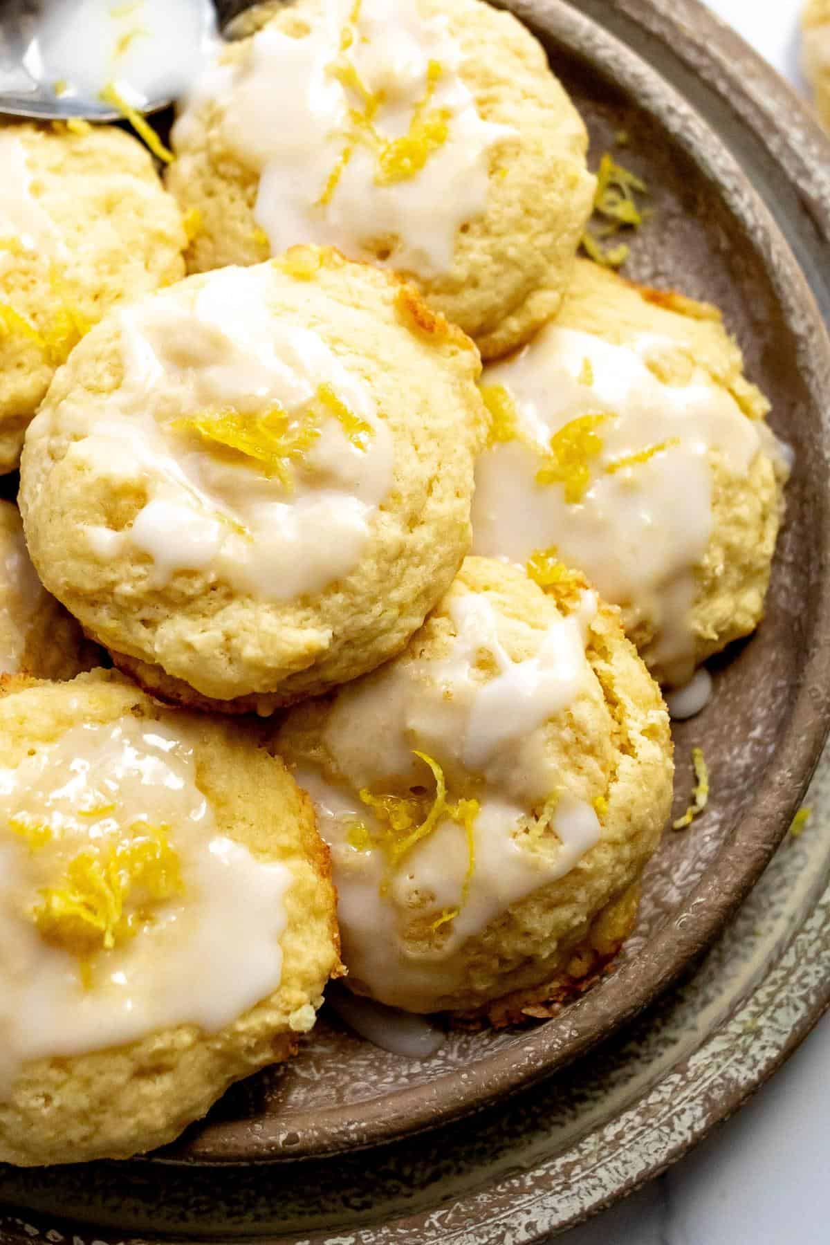 Lemon ricotta cookies on a beige plate with icing on top up close photo. 